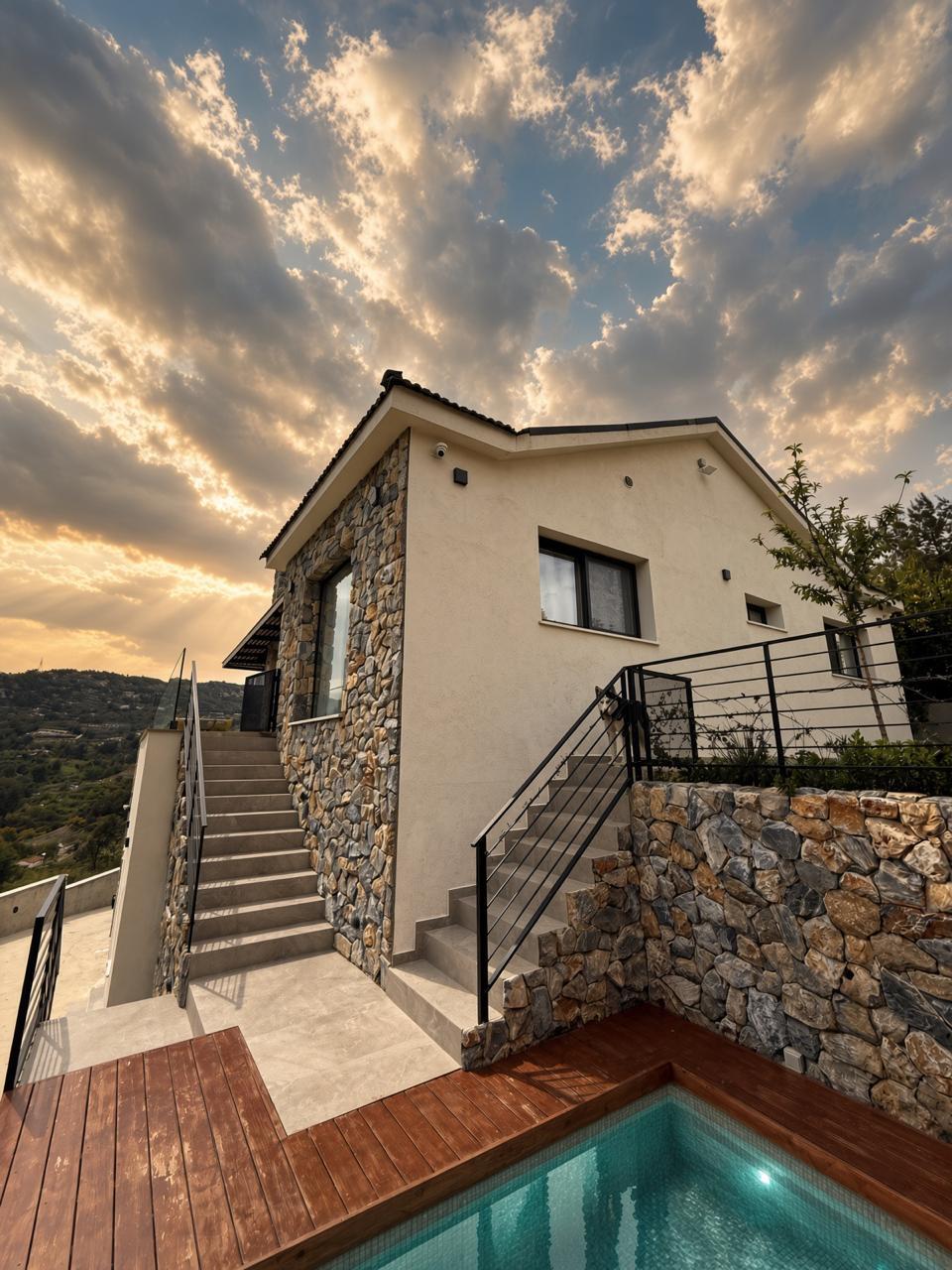 Cold plunge jacuzzi set into the timber deck beside the stone villa at sunset